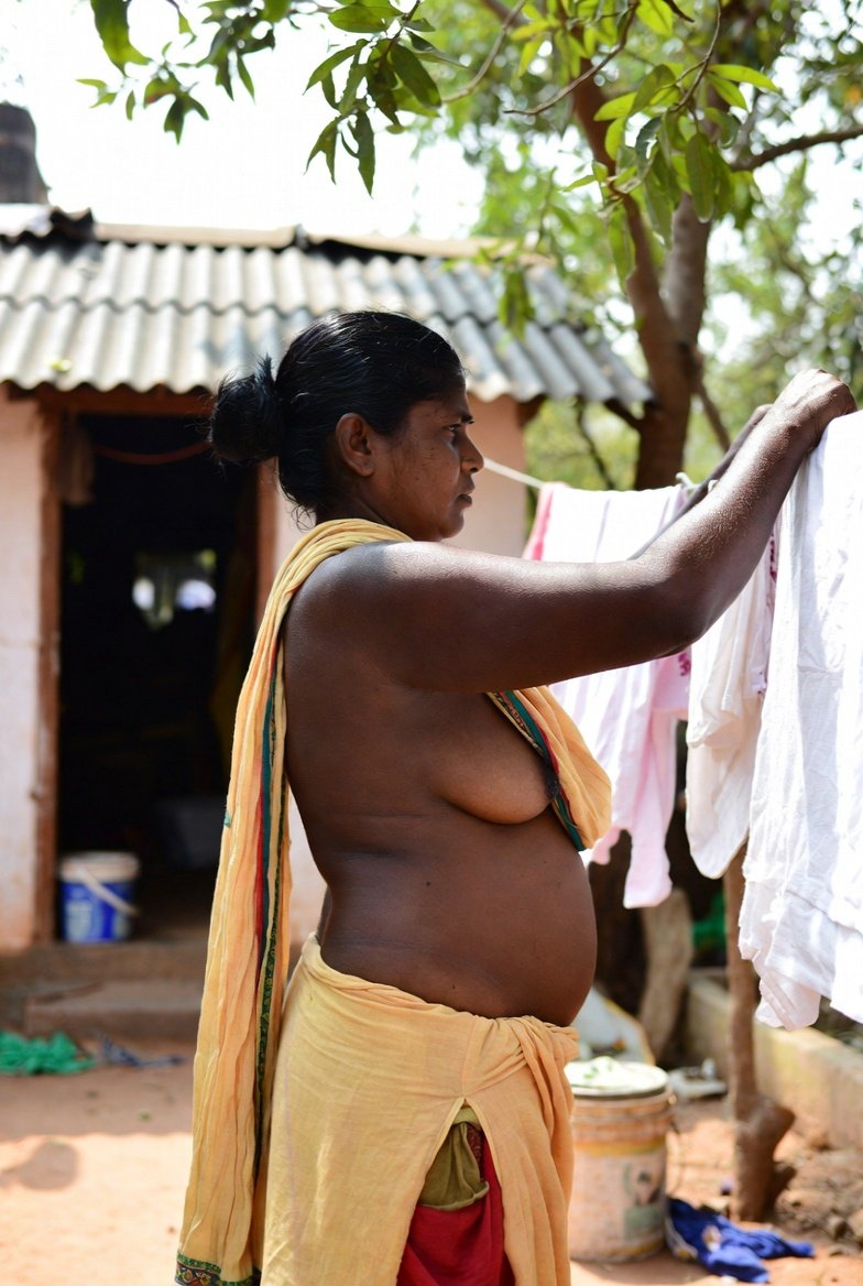 Curvy Indian aunty hanging clothes outside village home