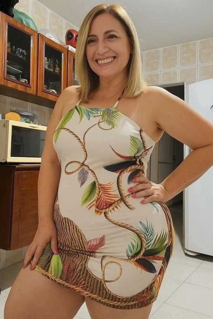 Golden-haired woman confidently posing in tropical-themed dress