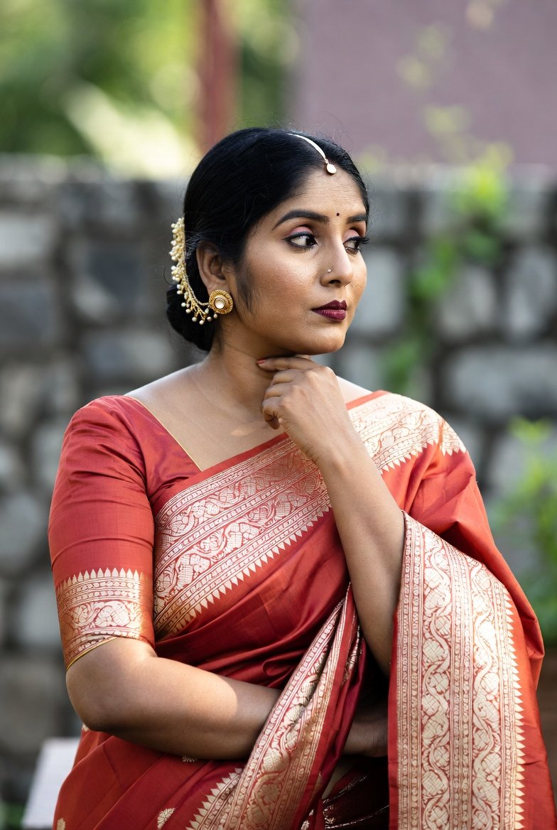 Desi woman in red saree with gold jewelry outdoors