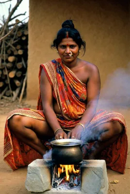 Voluptuous Indian woman in saree cooking over fire stove