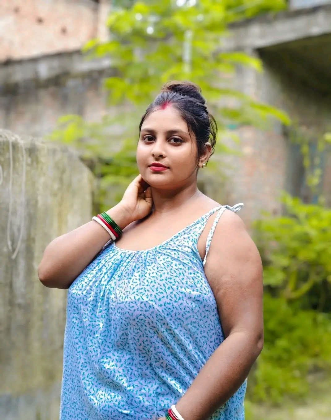 Curvy Indian bhabhi posing outdoors in light blue dress, showing off her curves