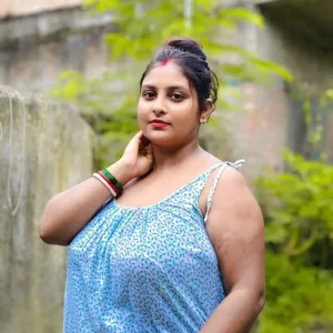 Curvy Indian bhabhi posing outdoors in light blue dress, showing off her curves