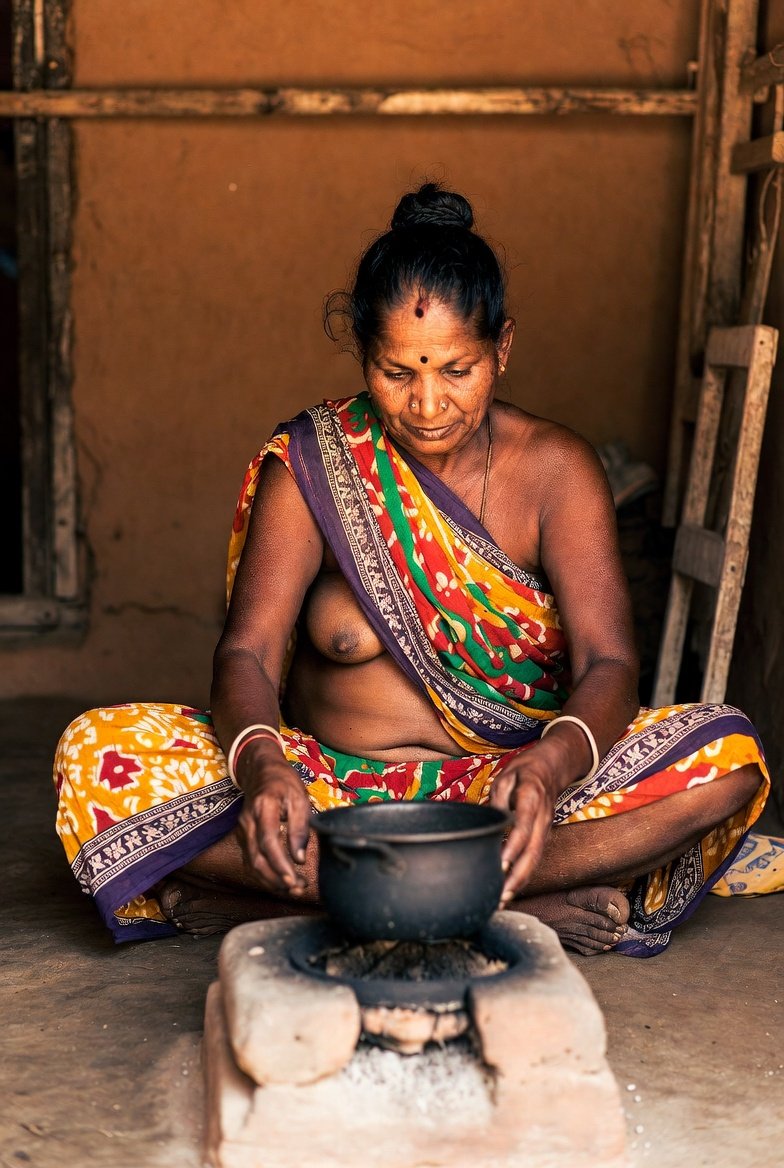 Mature Indian aunty in saree cooking in rustic kitchen