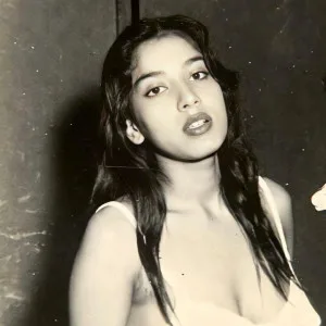 Indian woman revealing cleavage in white bra and dark room